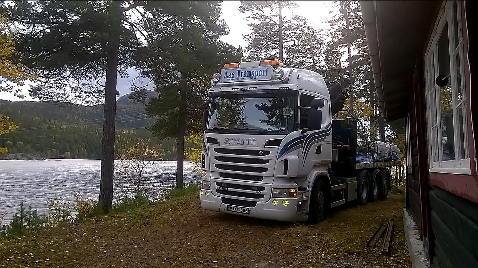 Hvit Scania med Aas Transport på solskjermen, parkert ved vann i Numedal.